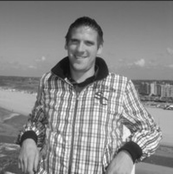 Laurens Cuelenaere in zwart-wit, lachend op een terras aan het strand