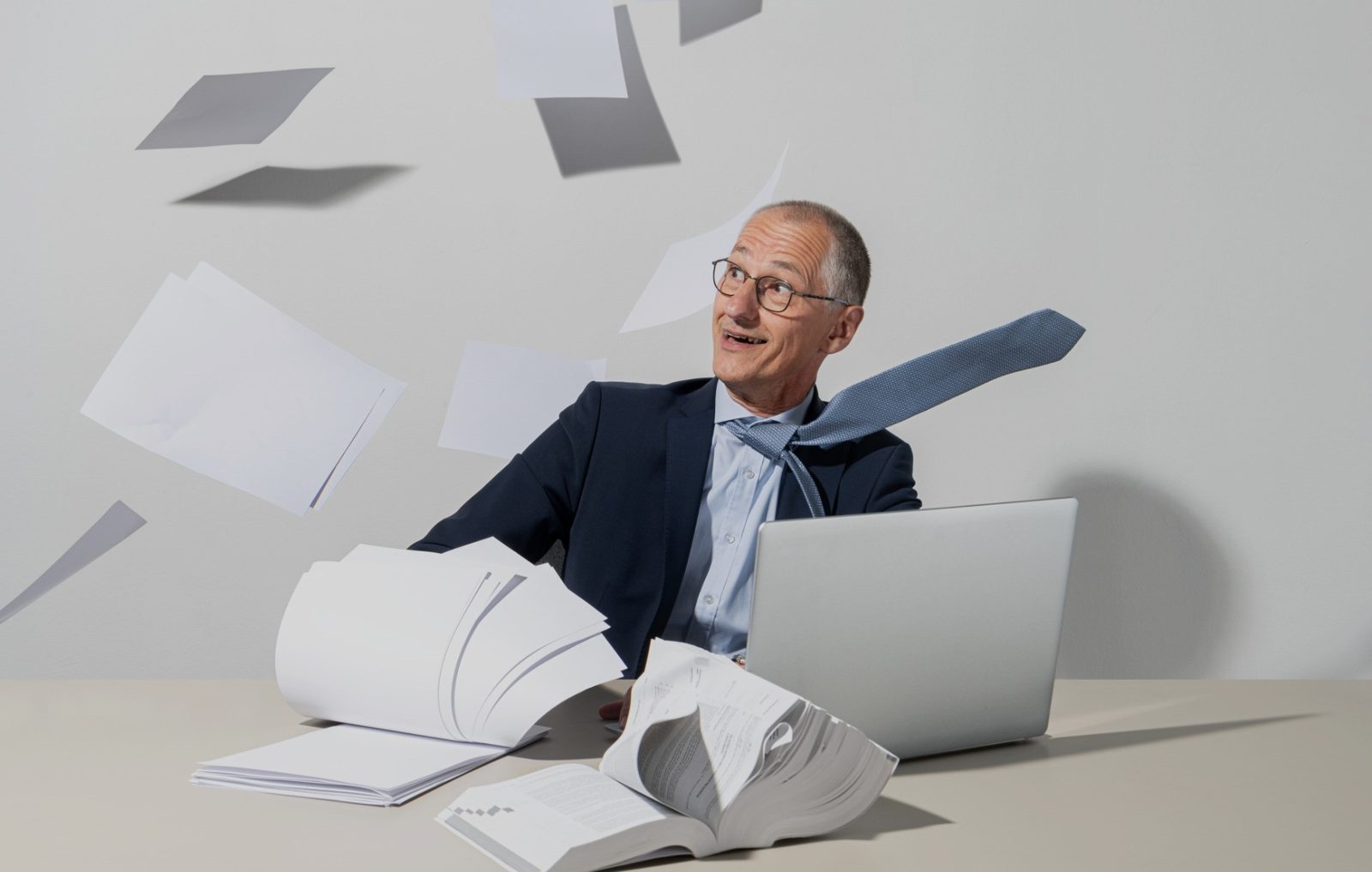 Collega achter zijn laptop terwijl papieren om hem heen wegwaaien